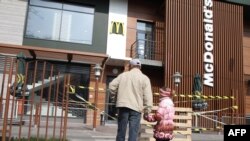 Мужчина с ребенком смотрят на закрытое помещение McDonald’s в Симферополе, 4 апреля 2014 года