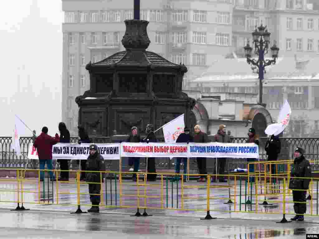 Несколько человек стоят непосредственно у Храма Христа Спасителя за двумя кольцами оцепления.