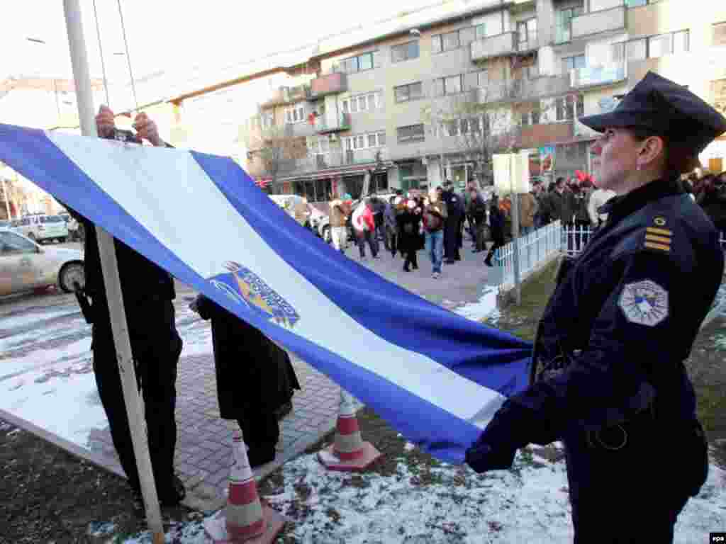 Полицейский в Приштине поднимает новый флаг после провозглашения независимости, 17 февраля 2008