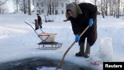 Старушка полощет белье в проруби на Сиверском озере в городке Кириллов