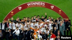 Italy -- Sevilla players and officials celebrate with the trophy after defeating Benfica in their Europa League final soccer match at the Juventus stadium in Turin, May 14, 2014